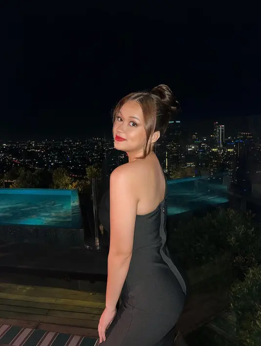 Rebecca Klopper tampil memukau dengan dress hitam berlengan asimetris dan pita merah. Rambutnya dihigh-bun dengan sedikit bagian depan rambutnya disisakan sebagai poni, makeup bold, dan pulasan lipstik warna merah. [Foto: Instagram/rklopperr]