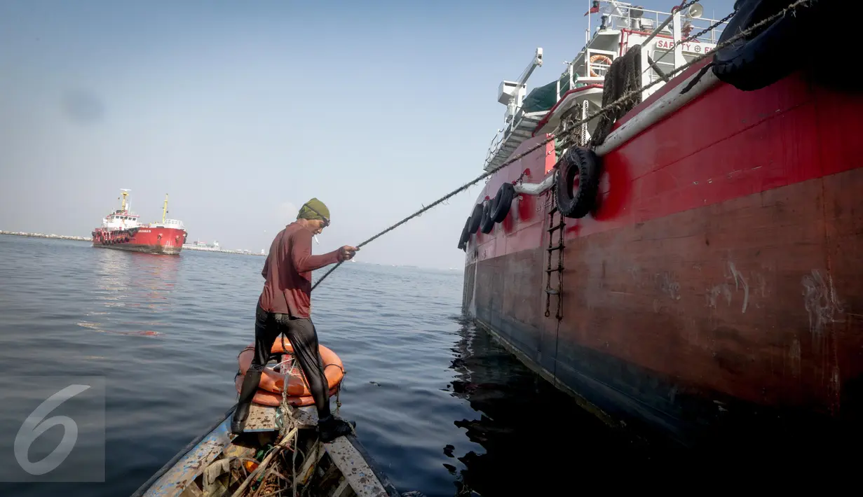 Supardi mengaitkan pengait untuk menahan kapal dari terjangan ombak  di perairan pesisir Cilincing, Jakarta, Jumat (17/3). (Liputan6.com/Faizal Fanani)
