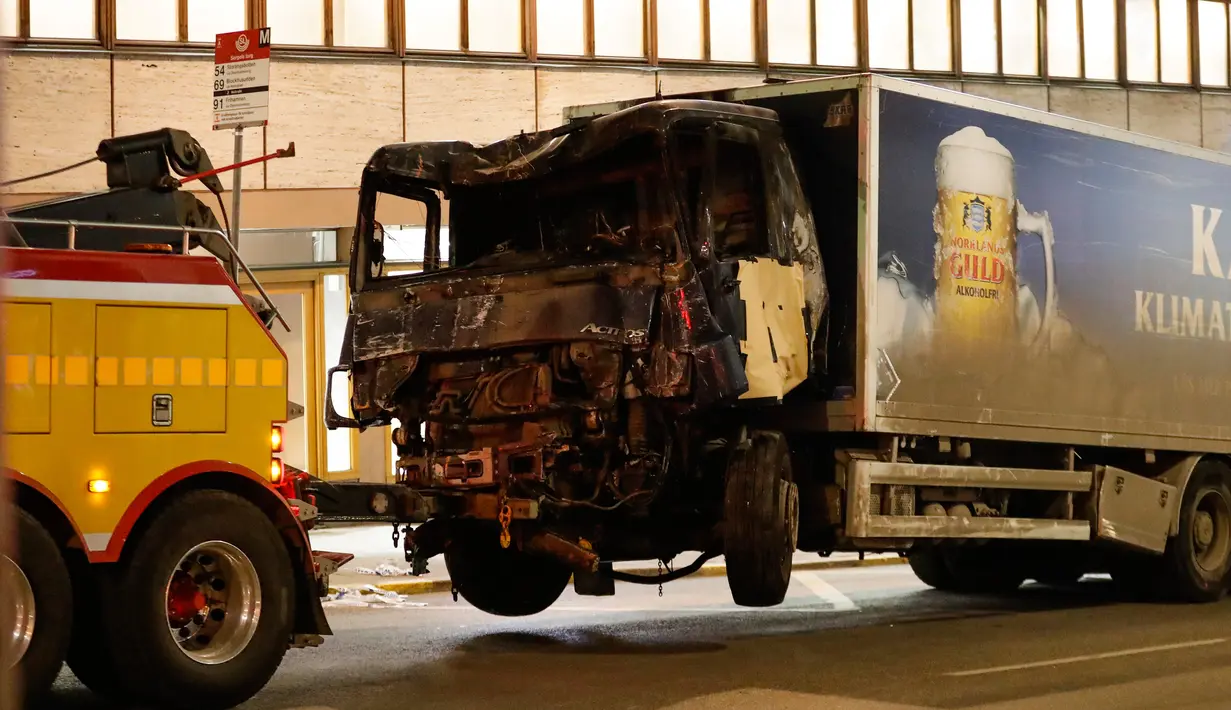 Petugas mengevakuasi truk yang rusak usai menabrak kerumunan orang di Jalan Drottninggatan, pusat kota Stockholm, Swedia (8/4). Perusahaan pemilik truk tersebut mengaku, sebelumnya truk dibajak pada hari yang sama. (AFP/Odd Andersen)