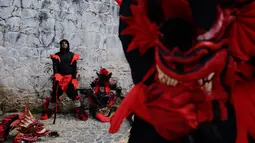 Seorang peserta mengenakan kostum setan beristirahat di sela-sela festival Congos and Devils di luar benteng San Jeronimo di Portobelo, Panama (18/3). (AP Photo/Arnulfo Franco)