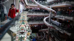 Pengunjung berjalan di dekat perosotan setinggi lima lantai yang dibangun di dalam salah satu pusat perbelanjaan di Shanghai, China, Selasa (16/2). Wahana permainan sepanjang 20 meter itu dibuka untuk umum pada 22 Februari mendatang. (REUTERS/Aly Song)