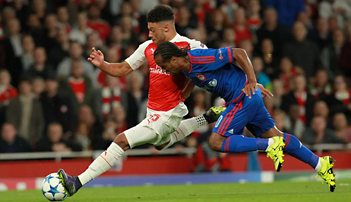 Pemain Arsenal, Alex Oxlade-Chamberlain berlari menghindari hadangan pemain Olympiacos, Leandro Salino pada laga Liga Champions di Stadion Emirates, Inggris, Rabu (30/9/2015). (EPA/Sean Dempsey)