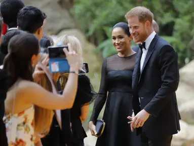 Pangeran Harry dan Meghan Markle tiba menghadiri pemutaran perdana film The Lion King di London (14/7/2019). Duchess of Sussex tampil menawan dalam balutan gaun hitam dengan detail lebar di bagian bawah rok. (AFP Photo/Tolga Akmen)