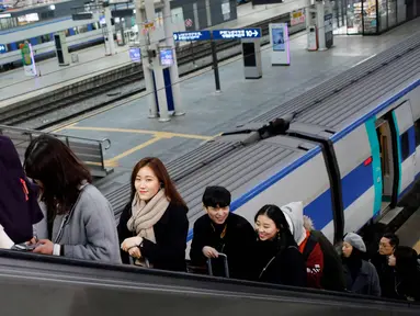 Sejumlah warga menggunakan eskalator di sebuah stasiun kereta api di Seoul, Korea Selatan, (19/2). (AFP Photo/David Gannon)
