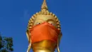 Masker diletakkan pada wajah patung Buddha raksasa di kuil Wat Nithet Rat Pradit di Pathum Thani di luar Bangkok, Thailand, 12 Mei 2020. Pemasangan masker tersebut sebagai tanggapan terhadap penyebaran pandemi Covid-19. (Photo by Mladen ANTONOV / AFP)