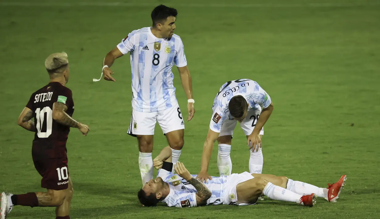 Pemain Argentina Lionel Messi (bawah) meringis kesakitan saat melawan Venezuela pada pertandingan kualifikasi Piala Dunia 2022 di Caracas, Venezuela, Kamis (2/9/2021). Argentina menang 3-1. (Miguel Gutierrez, Pool via AP)