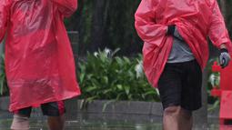 Warga menggunakan jas hujan berolahraga di kawasan Bundaran HI, Jakarta, Minggu (24/1/2021). Kepala BMKG Dwikorita mengatakan, puncak musim hujan akan terjadi pada Januari dan Februari 2021, sehingga perlu diwaspadai terjadinya cuaca ekstrem. (Liputan6.com/Herman Zakharia)