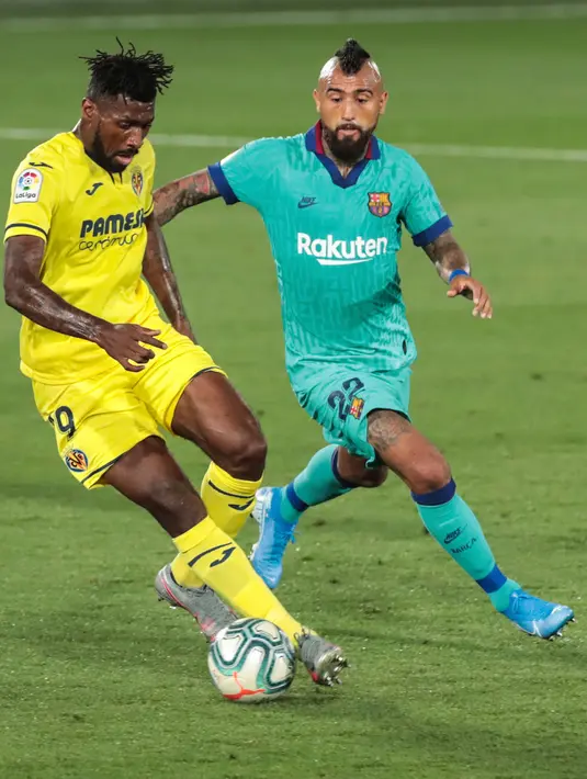 Pemain Villareal, Andre-Frank Zambo Anguissa berebut bola dengan gelandang Barcelona, Arturo Vidal dalam pekan ke-34 La Liga Spanyol di stadion La Ceramica, Minggu (5/7/2020). Barcelona sukses menumbangkan tim tuan rumah Villarreal dengan skor telak 4-1. (AP Photo/Jose Miguel Fernandez)