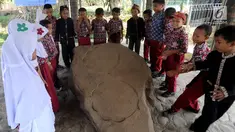 Murid SD melihat prasasti telapak kaki gajah di Prasasti Kebun Kopi, Ciaruteun Ilir, Bogor, Jawa Barat, Rabu (15/8). Prasasti ini peninggalan budaya Kerajaan Tarumanegara yang berdiri pada abad 4 hingga 7 masehi di Pasundan. (Merdeka.com/Arie Basuki)