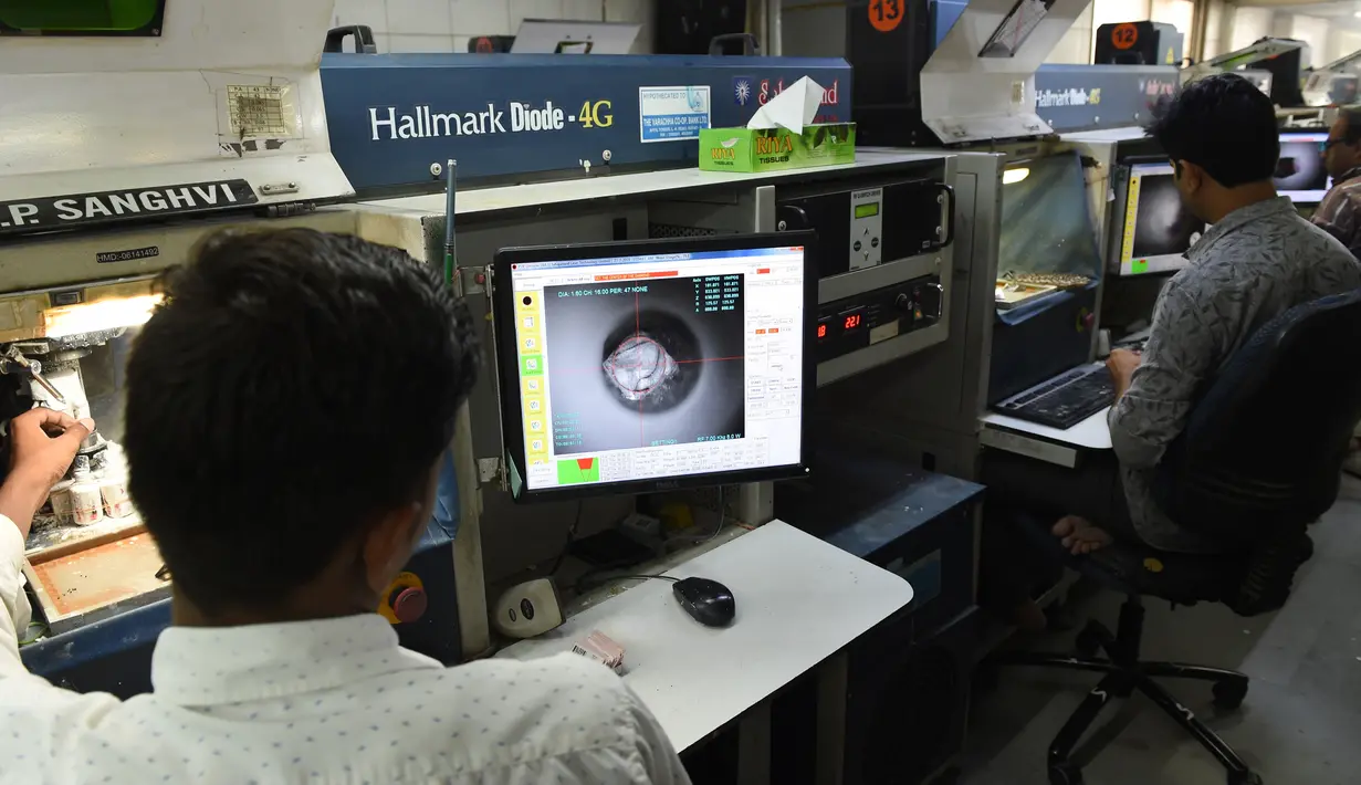 Pekerja menggunakan mesin laser mencari kotoran di dalam berlian di bengkel pemotongan dan pemolesan berlian di Ahmedabad (23/7/2019). India merupakan pusat pemotongan dan pemolesan berlian terbesar di dunia. (AFP Photo/Sam Panthaky)