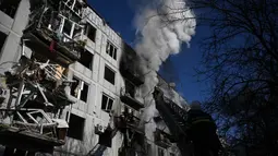 Petugas berusaha memadamkan kebakaran pada sebuah gedung setelah pemboman di Kota Chuguiv, Ukraina timur, 24 Februari 2022. Angkatan bersenjata Rusia mencoba menyerang Ukraina dari beberapa arah, menggunakan sistem roket dan helikopter untuk menyerang posisi Ukraina di selatan. (Aris Messinis/AFP)