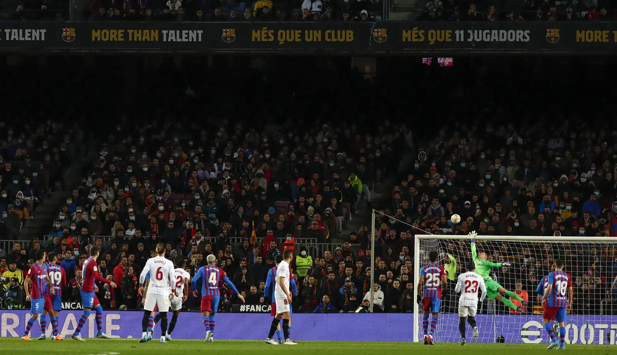 Kiper Barcelona, Marc-Andre ter Stegen melakukan penyelamatan saat bertanding melawan Sevilla pada pertandingan lanjutan La Liga Spanyol di stadion Camp Nou di Barcelona, Spanyol, Senin (4/4/2022). Tambahan tiga angka ini lantas membawa Barcelona naik dua peringkat sekaligus. (AP Photo/Joan Monfort)
