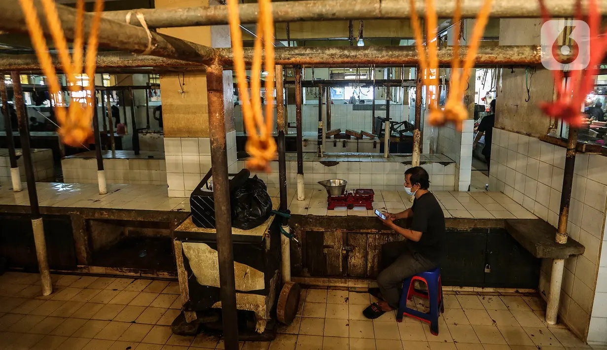 Seorang pria bermain smartphone di los pedagang yang kosong di Pasar Kebayoran, Jakarta, Rabu (20/1/2021). Para pedagang daging sapi di sejumlah pasar di kawasan Jakarta, Bogor, Depok, Tangerang, dan Bekasi (Jabodetabek) menggelar aksi mogok jualan hingga Jumat (22/1). (Liputan6.com/Johan Tallo)