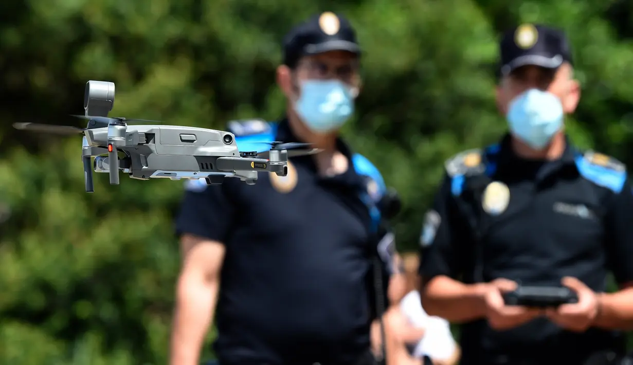 Polisi setempat menerbangkan sebuah drone atau pesawat tak berawak memperingatkan orang-orang untuk menjaga jarak di pantai Areas di Sanxenxo, Spanyol, Selasa (14/7/2020). Drone tersebut untuk memantau jaga jarak antarwisatawan saat berlibur di masa pandemi Corona. (MIGUEL RIOPA / AFP)