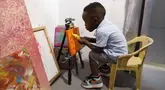 Ace-Liam Nana Sam Ankrah, yang akan berulang tahun ke dua pada bulan Juli, memamerkan tabung catnya di galeri seni ibunya di Accra, Ghana, pada 27 Mei 2024. (AP Photo/Misper Apawu)