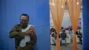 Petugas polisi menekan lengannya setelah menerima vaksinasi COVID-19 dosis ketiga di rumah sakit pemerintah di Gauhati, India (10/1/2022). India pada Senin (10/1) mulai memberikan dosis penguat (booster) vaksin COVID-19 bagi pekerja di lini depan dan lansia yang rentan.  (AP Photo/Anupam Nath)