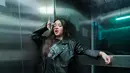Eca Aura berpose di dalam lift pakai outfit serba hitam. Ia padukan kaus hitam bermotif dengan jaket kulit, dan celana jeans abu-abu. [Foto: Instagram/elsaajapasal]