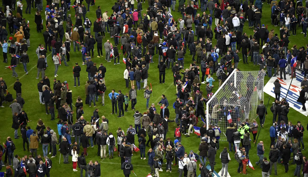 Suporter sepak bola berkumpul di lapangan menunggu izin keamanan untuk meninggalkan Stade de France di Saint-Denis, Paris, (13/11). Saksi mengatakan tiga ledakan terdengar di luar sebuah bar di dekat stadion Stade de France. (PHOTO/FRANCK FIFE)