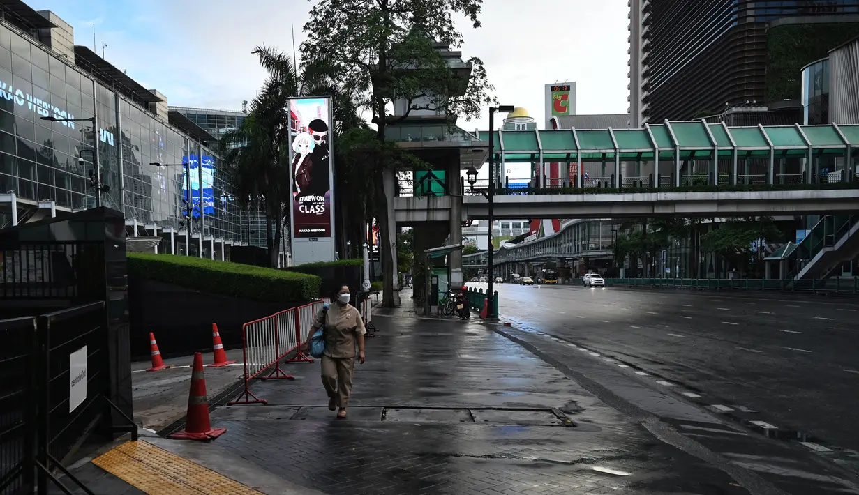 Seorang wanita melewati kompleks perbelanjaan Central World pada hari pertama penguncian COVID-19 yang lebih ketat di Bangkok, Senin (12/7/2021).  Thailand menerapkan lockdown untuk menekan laju penyebaran virus corona pada hari Senin di Bangkok dan provinsi sekitarnya. (Lillian SUWANRUMPHA/AFP)