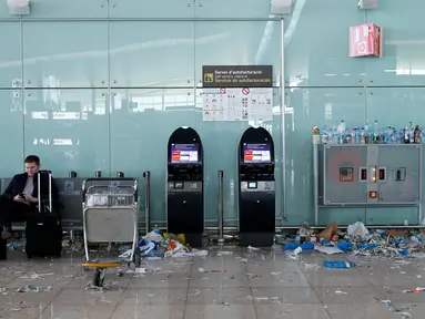 Seorang penumpang memainkan ponsel di antara sampah yang berserakan di Bandara Barcelona, Spanyol, Kamis (1/12). Para petugas kebersihan bandara tersebut menggelar aksi mogok kerja memprotes pengurangan anggaran sebesar 1,3 juta Euro. (REUTERS/Albert Gea)