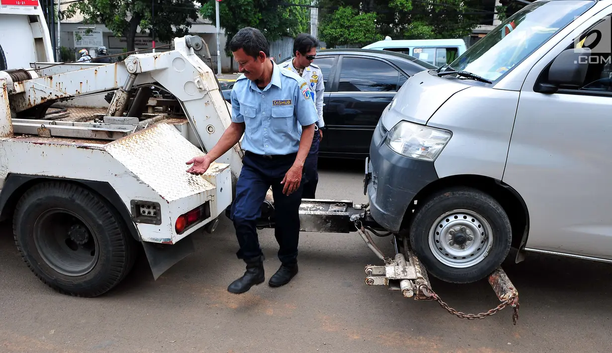Petugas Dinas Perhubungan DKI Jakarta memasang alat derek untuk membawa mobil yang parkir di bahu jalan di kawasan Jatinegara, Jakarta, Senin (2/10). Razia parkir liar dilakukan untuk menertibkan kawasan tersebut. (Liputan6.com/Helmi Afandi)