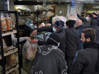 Orang-orang mengantre untuk mendapatkan roti di dalam toko roti di pinggiran selatan Beirut, Dahiyeh, Lebanon, pada 15 Maret 2022. Melonjaknya harga energi dan makanan yang dipicu oleh invasi Rusia ke Ukraina mendorong beberapa negara Timur Tengah ke tepi jurang. (AP Photo/Bilal Hussein)