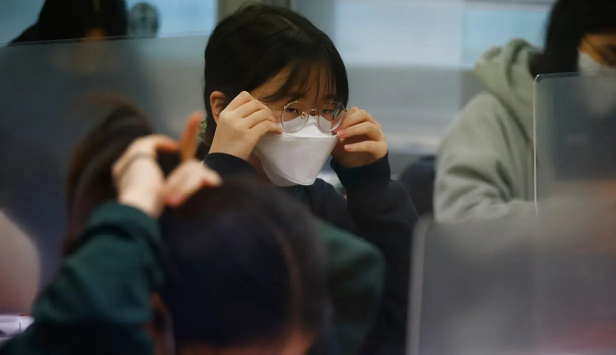 Siswa merapikan masker menunggu ujian masuk perguruan tinggi, Seoul, Korea Selatan, Kamis (3/12/2020). Di tengah pandemi COVID-19, pejabat Korea Selatan mendesak orang untuk tetap di rumah karena sekitar setengah juta siswa mempersiapkan ujian masuk perguruan tinggi. (Kim Hong-Ji/Pool Photo via AP)