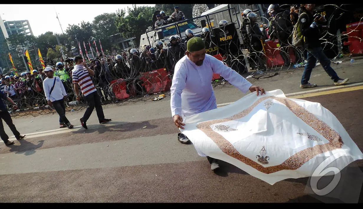 Seorang pendukung Prabowo menghamparkan sorbannya di depan penjagaan aparat saat mendengar kabar gugatan Prabowo dikabulkan MK, Jakarta, Kamis (21/08/2014) (Liputan6.com/Faisal Fanani)