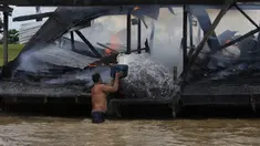 Penambang emas ilegal memadamkan api yang membakar tongkang di Sungai Madeira, Borba, Amazonas, Brasil, 28 November 2021. Institut Lingkungan dan Sumber Daya Alam Terbarukan Brasil membakar lebih dari 60 tongkang untuk menahan penambangan emas ilegal di anak Sungai Amazon. (AP Photo/Edmar Barros)