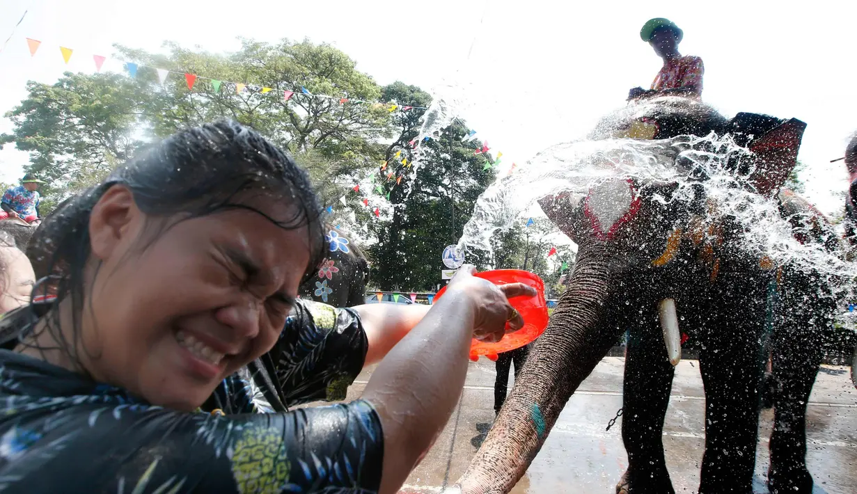 Seorang wanita menyiramkan air dalam perayaan festival air Songkran di provinsi Ayutthaya, utara Bangkok, Thailand, (11/4). Selama perayaan Songkran, warga melakukan perang air di jalanan dan di tempat umum. (AP Photo/Sakchai Lalit)