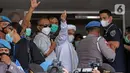 Rizieq Shihab (tengah) melambaikan tangan sesaat sebelum masuk gedung utama Mapolda Metro Jaya, Jakarta, Sabtu (12/12/2020). Rizieq Shihab akan menjalani pemeriksan sebagai tersangka penghasutan dan kerumunan di tengah pandemi Covid-19. (Liputan6.com/Helmi Fithriansyah)