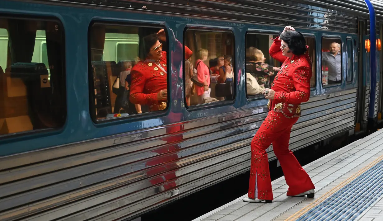 Penggemar Elvis Presley bercermin sebelum menaiki kereta untuk menghadiri The Parkes Elvis Festival di Stasiun Central, Sydney, Kamis (10/1). Festival yang digelar pertama kali pada tahun 1993 tersebut menampilkan semua hal dari Elvis. (PETER PARKS/AFP)