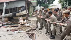Petugas Satpol PP menarik tali untuk merobohkan bangunan liar di Jalan Desa Semanan, Kalideres, Jakarta Barat, Senin (9/4). Penertiban dilakukan karena bangunan liar tersebut berdiri di atas tanah saluran air. (Liputan6.com/Arya Manggala)