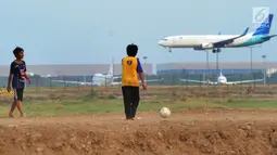 Anak-anak bermain bola di kawasan proyek perluasan landasan pacu atau Runway 3A Bandara Soekarno-Hatta (Soetta), Rawa Bokor, Tangerang, Banten, Selasa (2/7/2019). Mereka memanfaatkan lahan kosong yang belum dikerjakan pihak kontraktor untuk bermain bola. (merdeka.com/Arie Basuki)