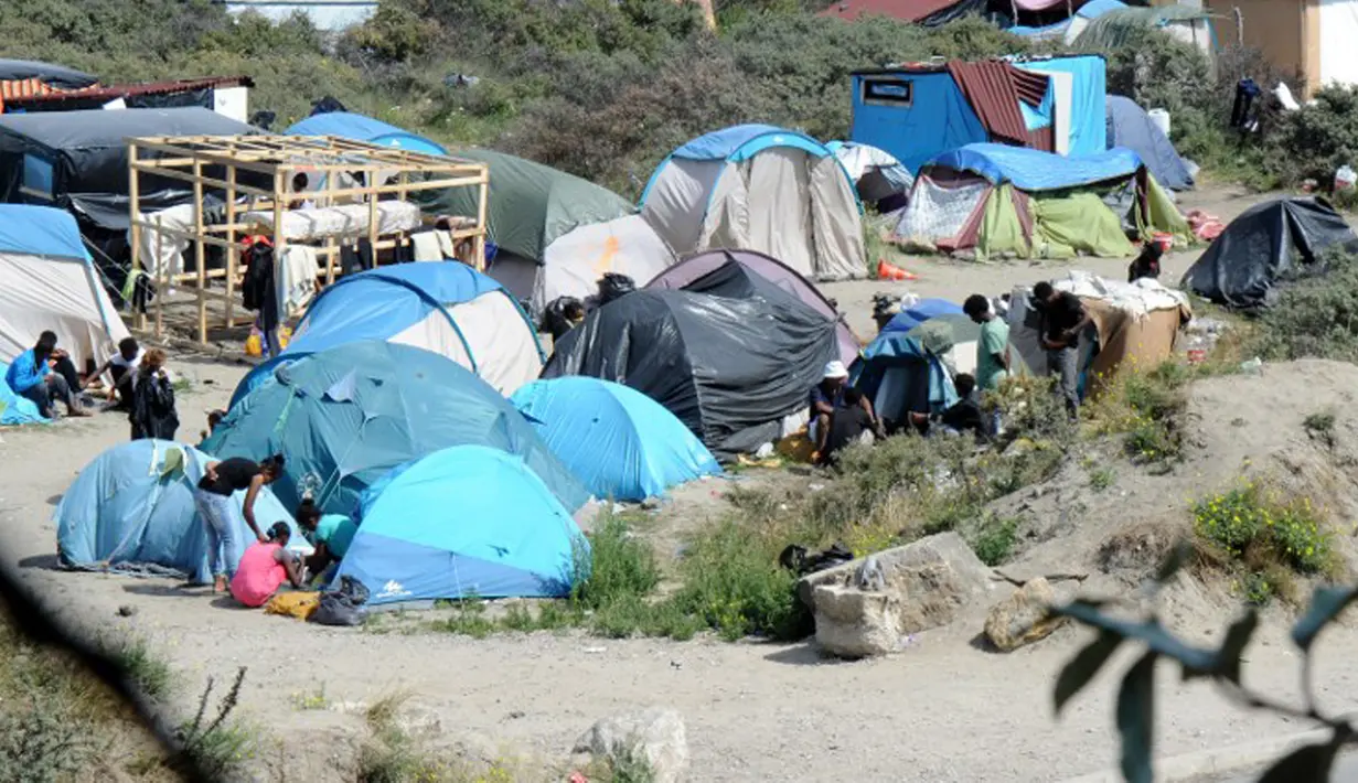 Imigran gelap berjalan di dekat puluhan tenda yang didirikan di sebuah kamp sementara di sekitar pelabuhan Calais, Prancis, Minggu (2/8/2015). Sebelumnya, ratusan imigran memaksa masuk Prancis melalui Terowongan Channel. (AFP PHOTO/FRANCOIS LO PRESTI)