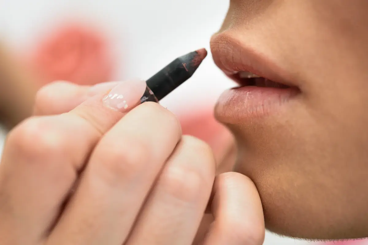 Seorang perempuan sedang mengaplikasikan lip liner di bibirnya (Foto Dok: Freepik/javi_indy)