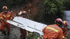 Petugas membawa puing di lokasi kecelakaan pesawat China Eastern di Kabupaten Tengxian di Daerah Otonomi Guangxi Zhuang, China selatan (24/3/2022). Area pencarian diperluas dalam pencarian korban dan kotak hitam kedua pesawat dengan 132 orang itu. (Lu Boan/Xinhua via AP)