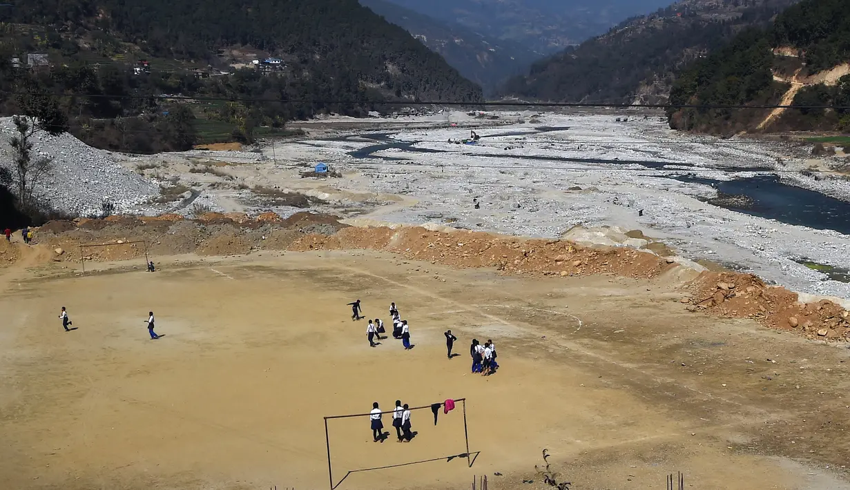 Anak-anak sekolah bermain sepak bola di lapangan yang berada di Bahuneypati, Sindhupalchok, sekitar 70 Kilometer timur laut Kathmandu, Nepal, 15 Februari 2018. Di sini kita bisa bermain bola di antara pegunungan Nepal yang megah. (PRAKASH MATHEMA/AFP)