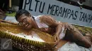 Seorang petani saat menggelar aksi menanam padi di depan Kedubes Jepang, Jakarta, Senin (5/12). Dalam aksinya, mereka menuntut ganti rugi paska penutupan akses lahan pertanian mereka karena pembangunan PLTU batu bara Batang. (Liputan6.com/Faizal Fanani)