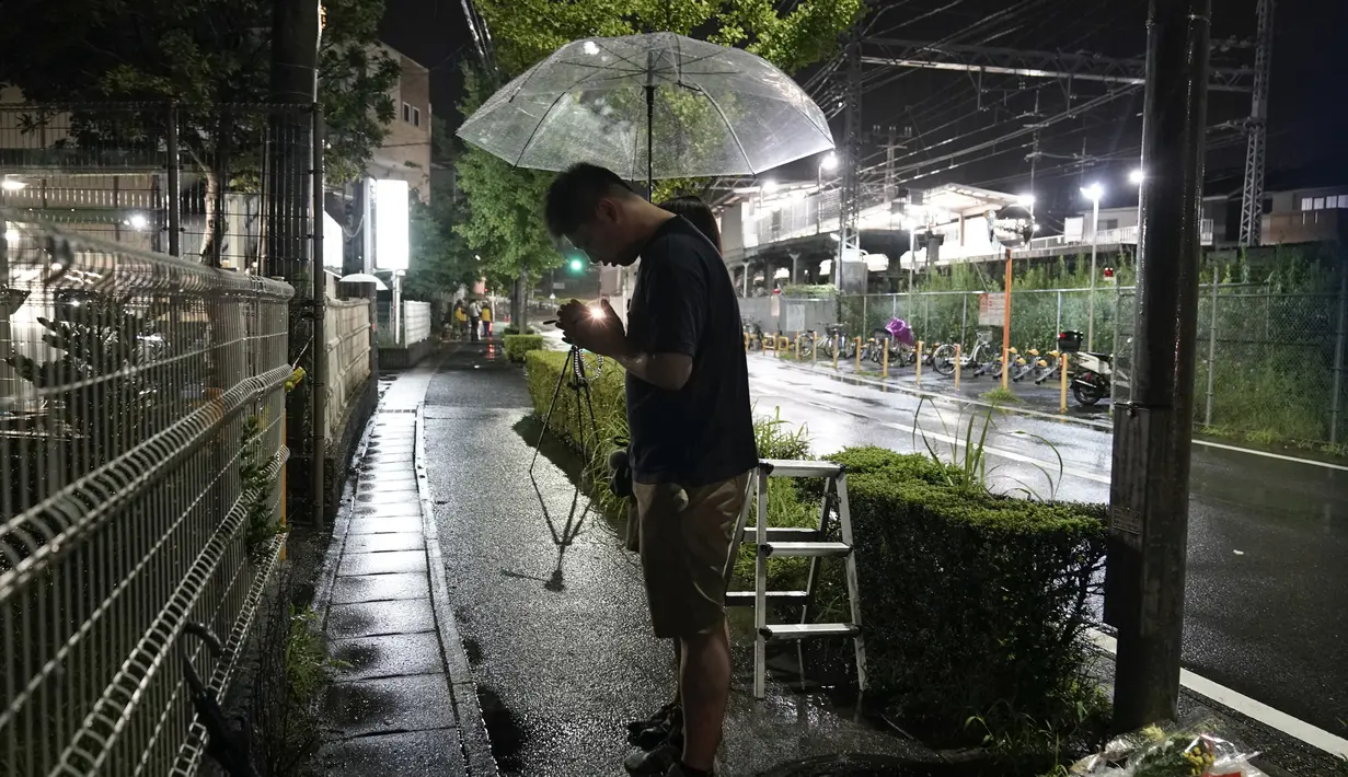 Suami istri berdoa untuk para korban setelah meletakkan bunga di luar gedung Kyoto Animation Studio di Kyoto, Jepang (19/7/2019). Stasiun televisi NHK melapor, seorang pria yang menuangkan bensin ke sekitar gedung animasi telah ditahan. (AP Photo/Jae C. Hong)