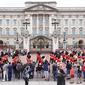 Orang-orang menyaksikan menyaksikan Band of The Coldstream Guards berbaris selama upacara Pergantian Penjaga di Istana Buckingham, London, yang berlangsung untuk pertama kalinya sejak dimulainya pandemi corona Covid-19 pada Senin (23/8/2021). (Kirsty O'Connor/PA via AP)