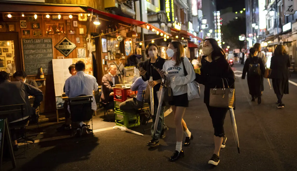 Sejumlah wanita berjalan sementara yang lain makan dan minum di restoran dan bar pada malam pertama pencabutan status darurat virus corona oleh pemerintah di Tokyo, Jepang, Jumat (1/10/2021). (AP Photo/Hiro Komae)