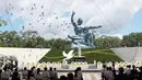 Merpati terbang di atas Patung Perdamaian selama upacara di Taman Perdamaian Nagasaki di Nagasaki, Jepang selatan, Senin (9/8/2021). Kota Nagasaki di Jepang pada hari Senin menandai peringatan ke-76 bom atom AS. (Kyodo News via AP)