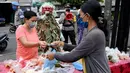 Polisi mengenakan topeng menyeramkan yang disebut "Leak" saat sosialisasi langkah-langkah pencegahan COVID-19 di pasar tradisional di Kerobokan, Denpasar, Kamis (14/5/2020). Kegiatan itu untuk mengimbau masyarakat terus melakukan berbagai upaya pencegahan penyebaran COVID-19. (SONNY TUMBELAKA/AFP)
