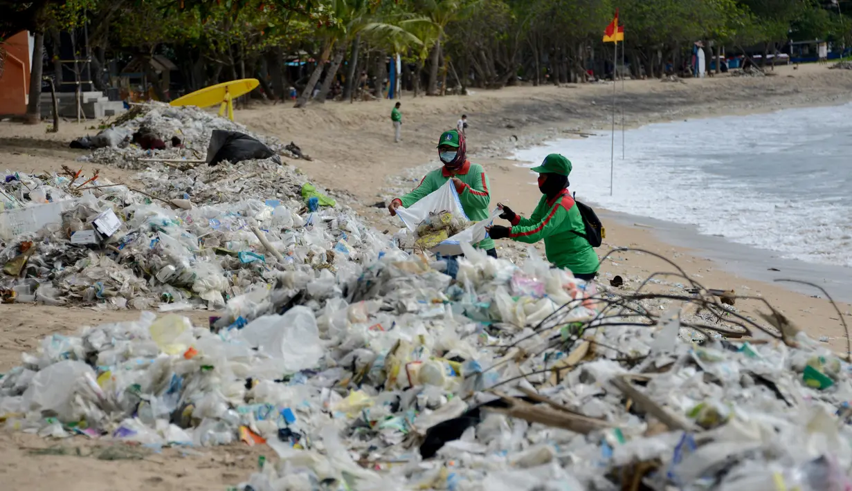 <p>Pekerja mengumpulkan sampah plastik saat membersihkan pantai Kuta dekat Denpasar di pulau wisata Bali (6/1/2021). Pada 1 Januari 2021, sekira 30 ton sampah diangkut dari kawasan Pantai Kuta dalam kegiatan bersih-bersih pantai. (AFP/Sonny Tumbelaka)</p>