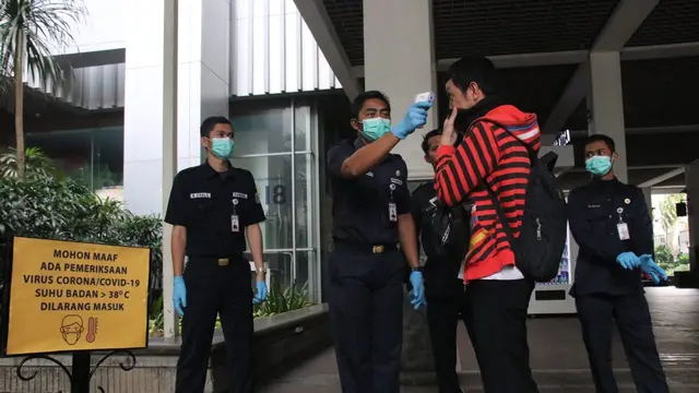Petugas mengecek suhu tubuh pegawai di lingkungan Pemprov DKI Jakarta