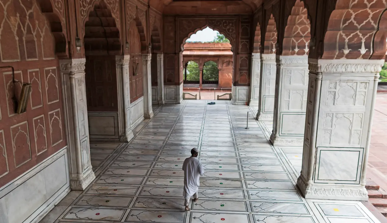 Pengurus berjalan seusai menempelkan stiker jaga jarak di lantai Masjid Jama yang dibuka kembali setelah pelonggaran lockdown di kawasan Kota Tua Delhi, Selasa (7/7/2020). India pada 6 Juli menjadi negara dengan jumlah virus corona tertinggi ketiga di dunia. (XAVIER GALIANA/AFP)