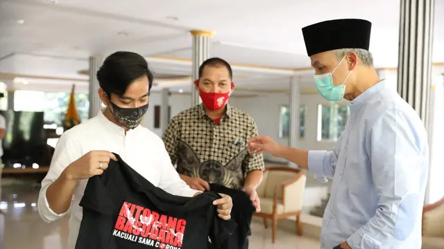 Gibran menyerahkan kaos kepada Ganjar Pranowo. (Foto: Liputan6.com/Felek Wahyu)