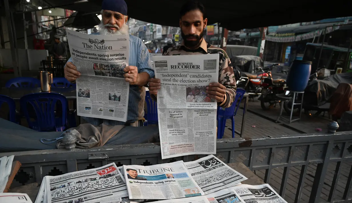 Orang-orang membaca koran pagi dengan berita utama pemilu di halaman depan di sebuah kios pinggir jalan sehari setelah pemilihan umum nasional Pakistan di Lahore pada tanggal 9 Februari 2024. (Aamir Qureshi/AFP)