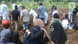 Keluarga menyaksikan pemakaman jenazah korban COVID-19 di TPU Tegal Alur, Jakarta, Kamis (17/12/2020). Hingga hari ini, intensitas pemakamanan korban covid-19 di DKI masih tinggi dengan rata-rata yang dimakamkan mencapai 30 hingga 38 jenazah per hari. (merdeka.com/Arie basuki)